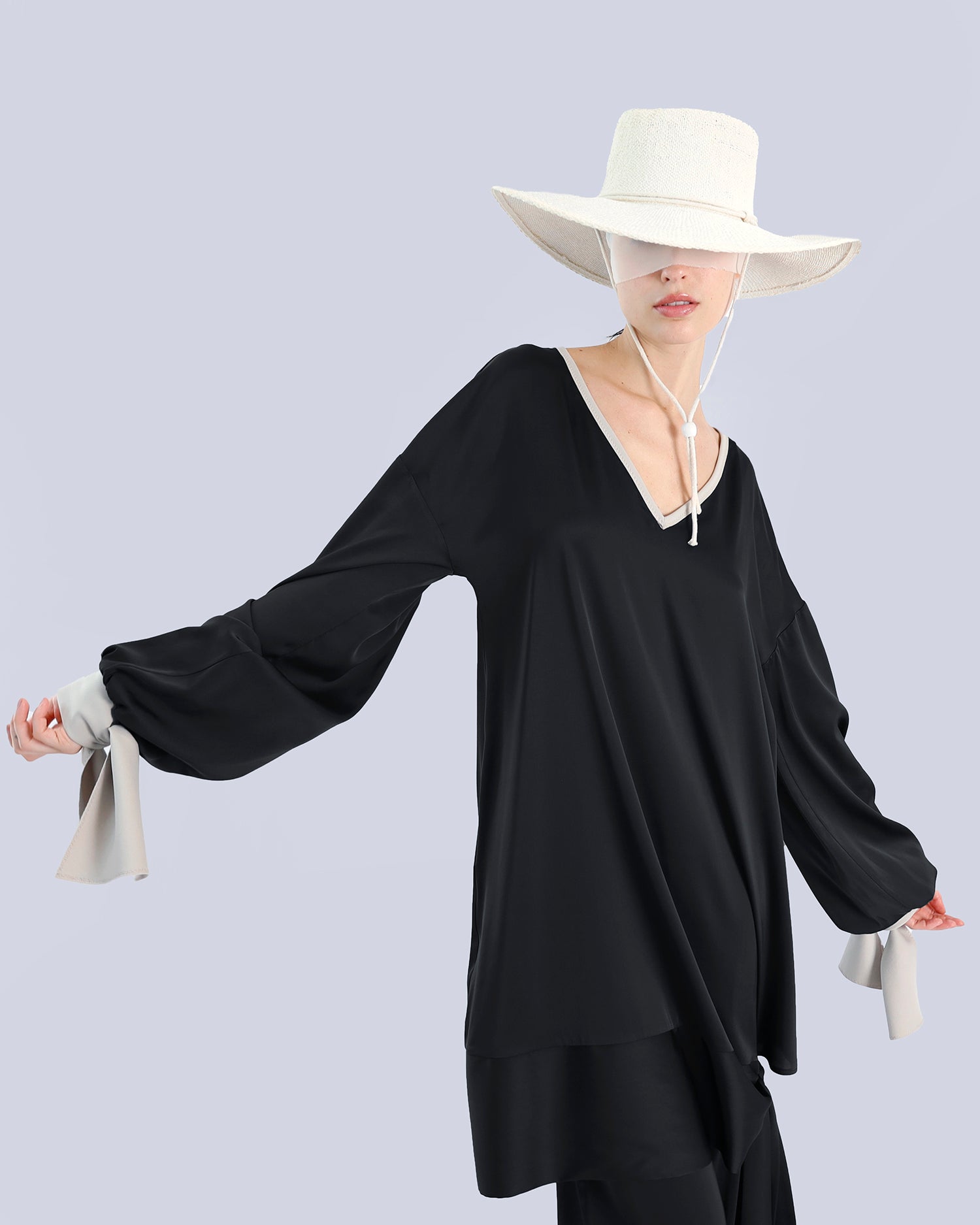 Person wearing a black outfit with wide sleeves and a white hat on a light gray background. Maison Marie Saint Pierre | Tunique | PELLEGRINA | Black-Fog | Pants | PAMELA | Black 