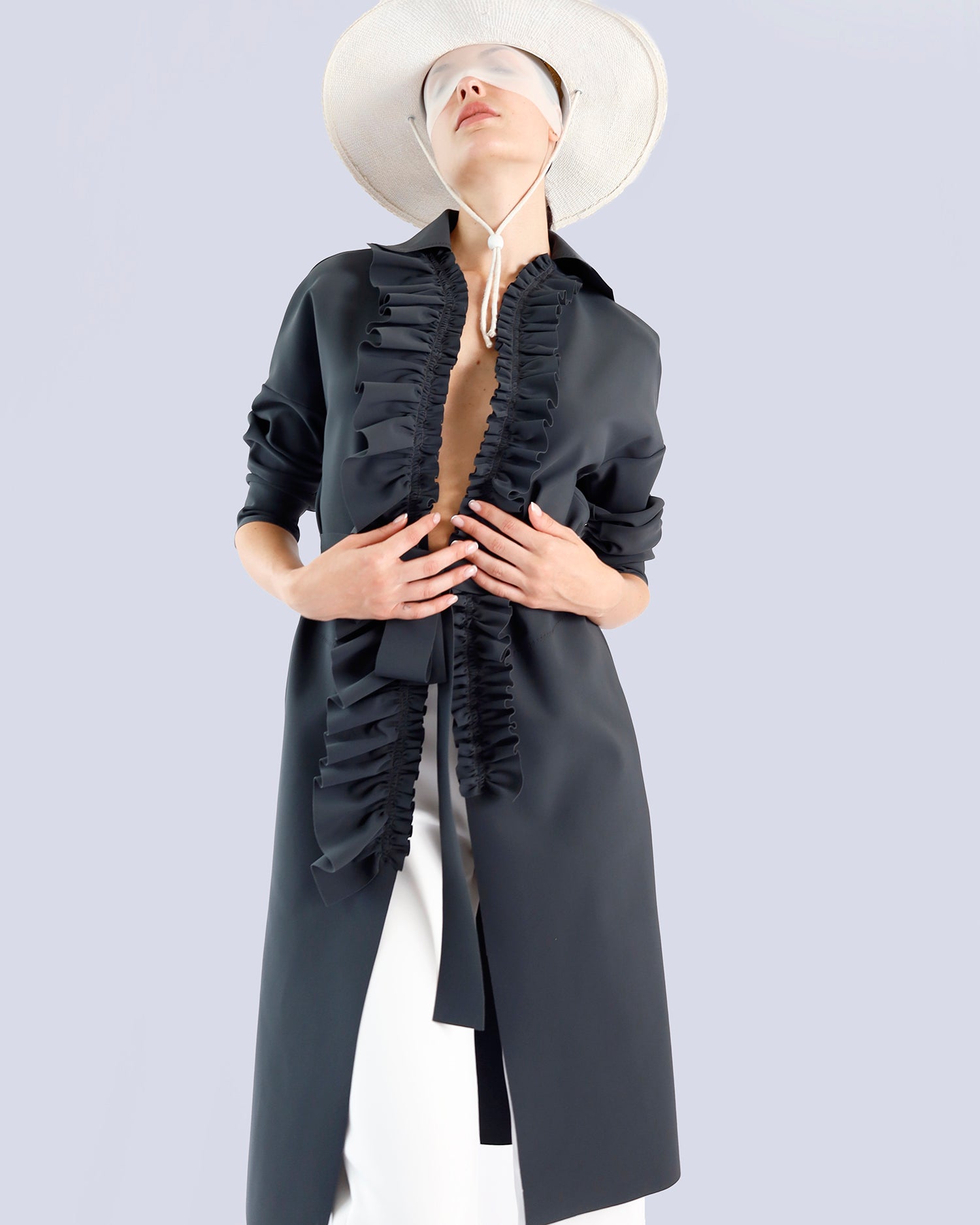 Person wearing a long black coat with ruffled details on a light gray background. Maison Marie Saint Pierre | Coat | PELLINAME | ANT