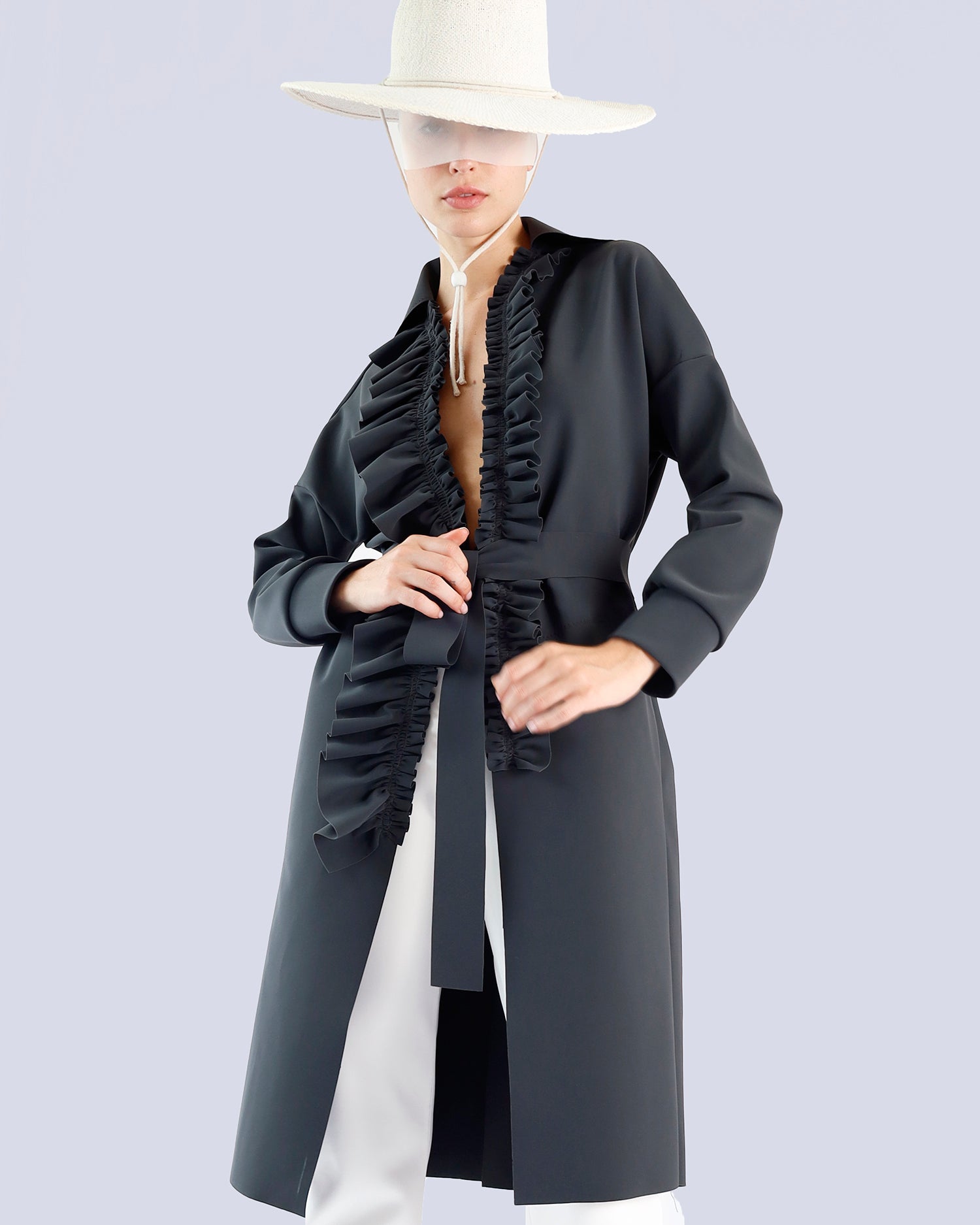 Person wearing a long black coat with ruffled details on a light gray background. Maison Marie Saint Pierre | Coat | PELLINAME | ANT