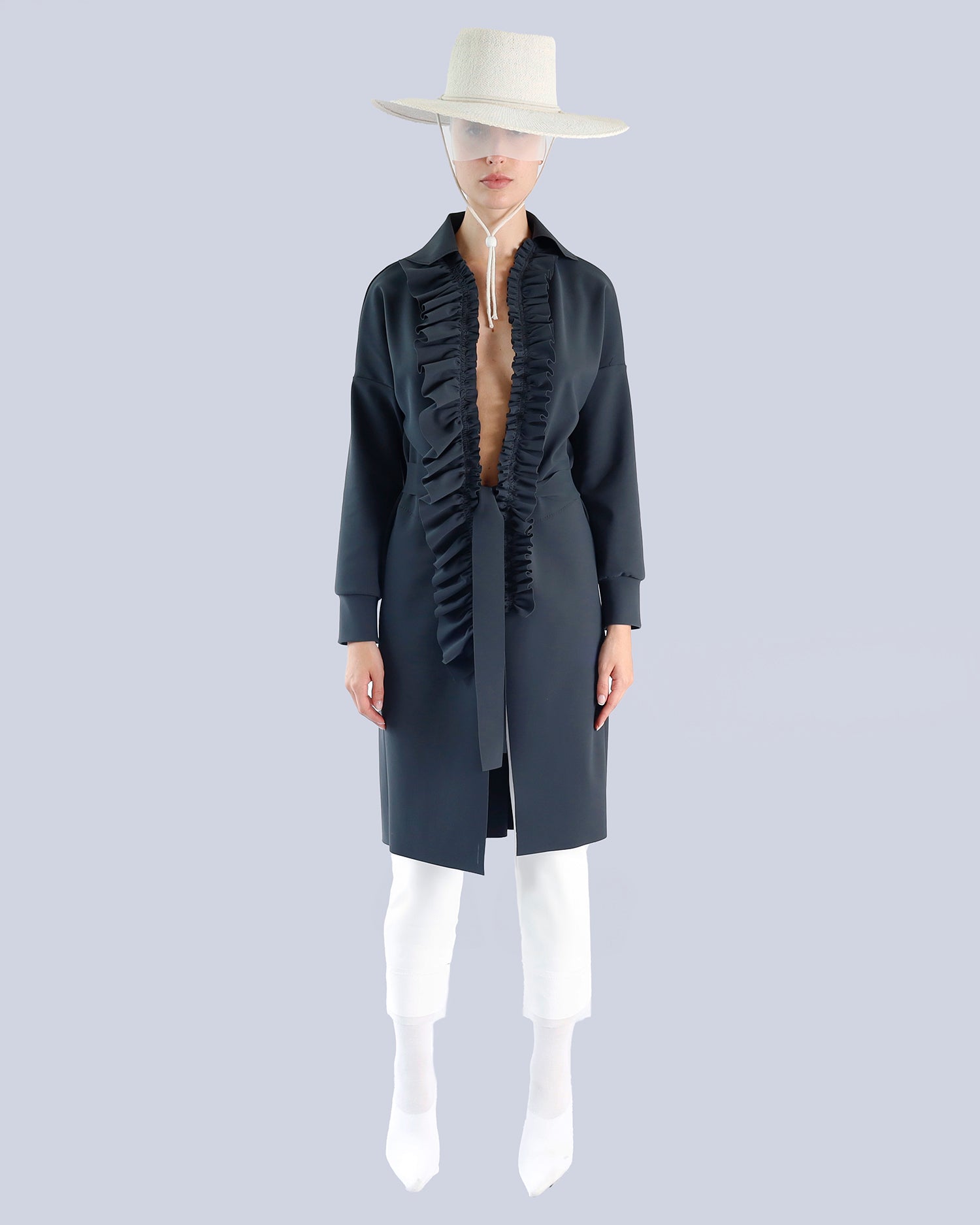 Mannequin wearing a long dark coat with fringes and a white hat on a light gray background. Maison Marie Saint Pierre | Coat | PELLINAME | ANT