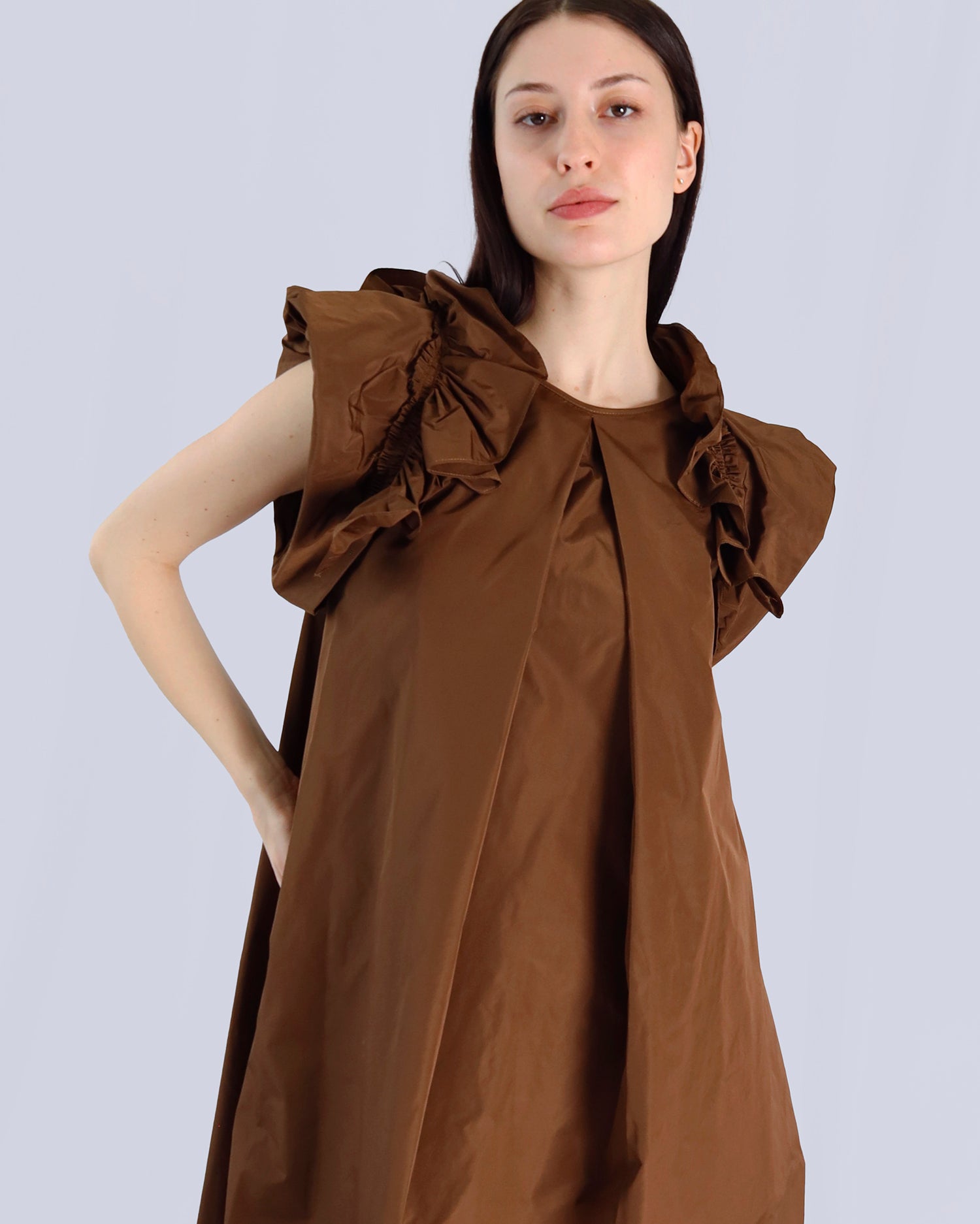 Woman wearing a brown dress with ruffled shoulders against a light gray background. Maison Marie Saint Pierre | Dress | PAVOLINE | DUM 