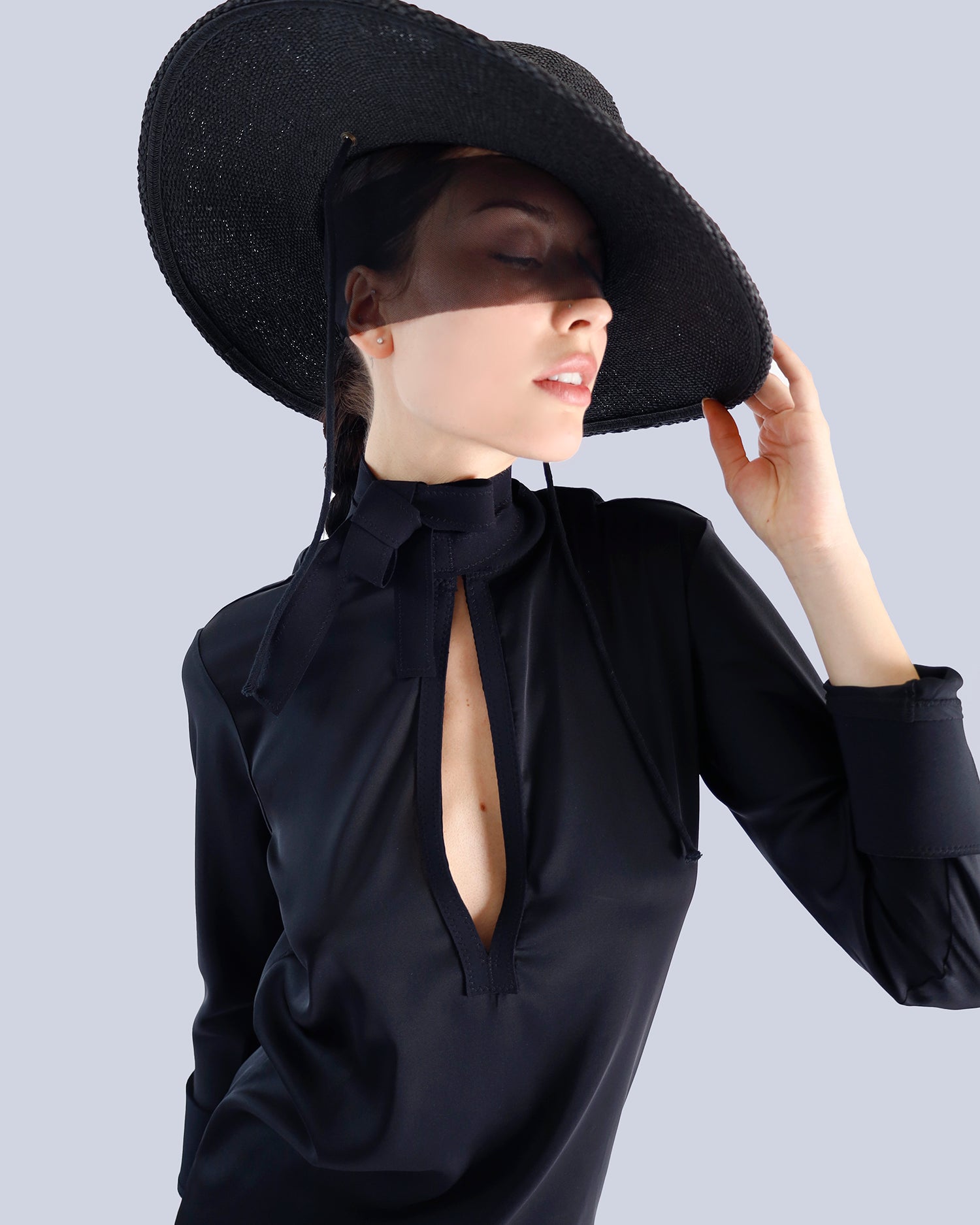 Woman wearing a black hat and black blouse with a deep neckline on a light gray background. Maison Marie Saint Pierre | Dress | PATTI | Black 