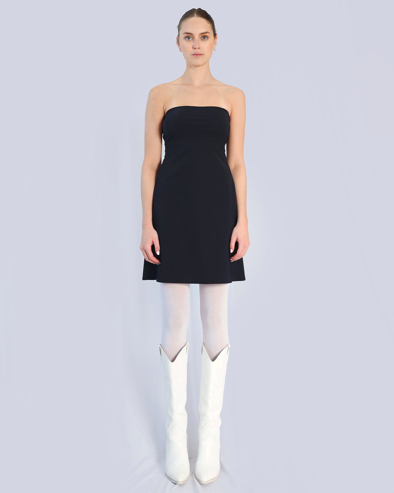 Woman wearing a black strapless dress and white knee-high boots on a light gray background. Maison Marie Saint Pierre | Dress | PHASMINA | Black