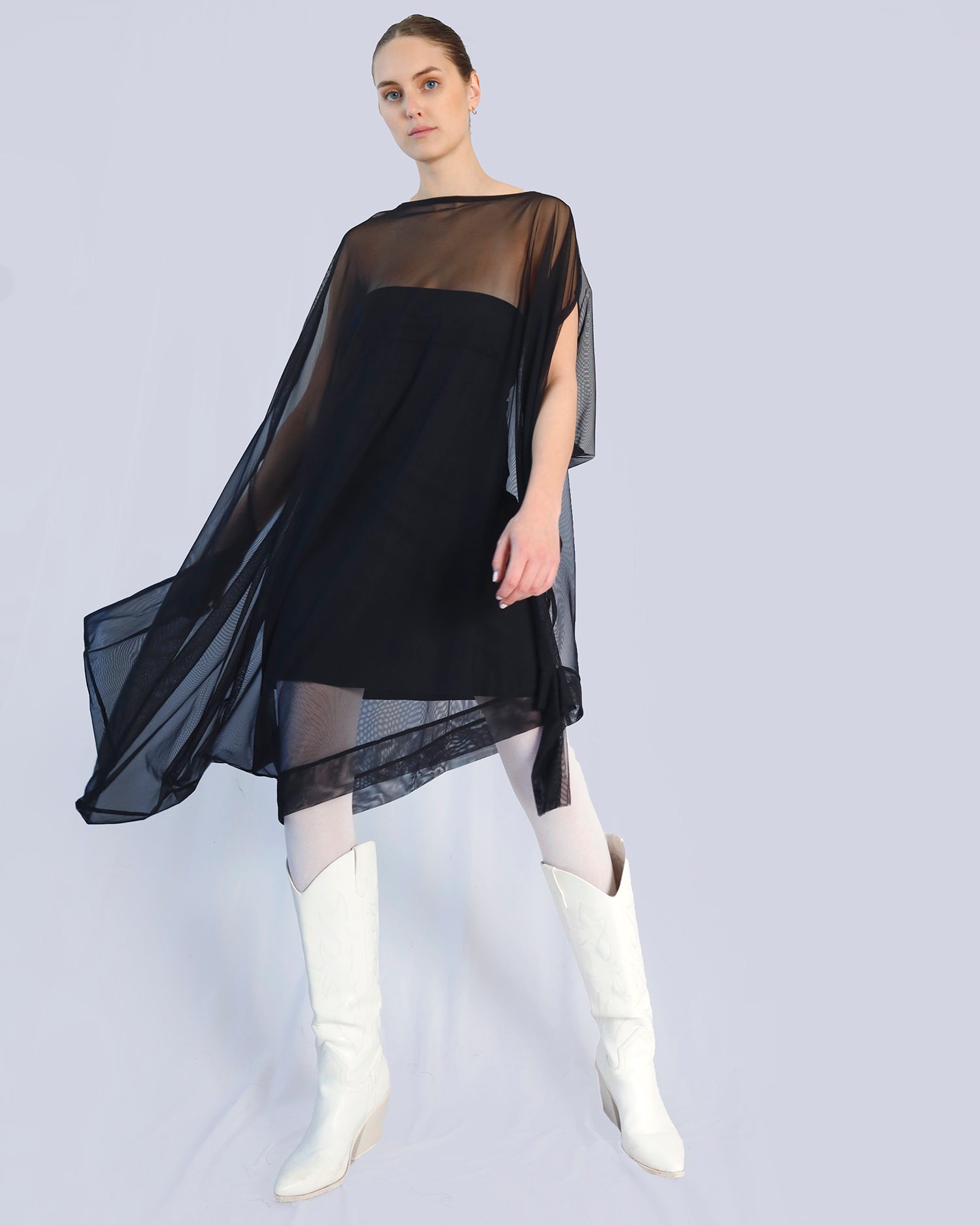 Woman wearing a black dress with sheer sleeves and white boots on a light gray background. Maison Marie Saint Pierre | Dress | PHASMINA | Black